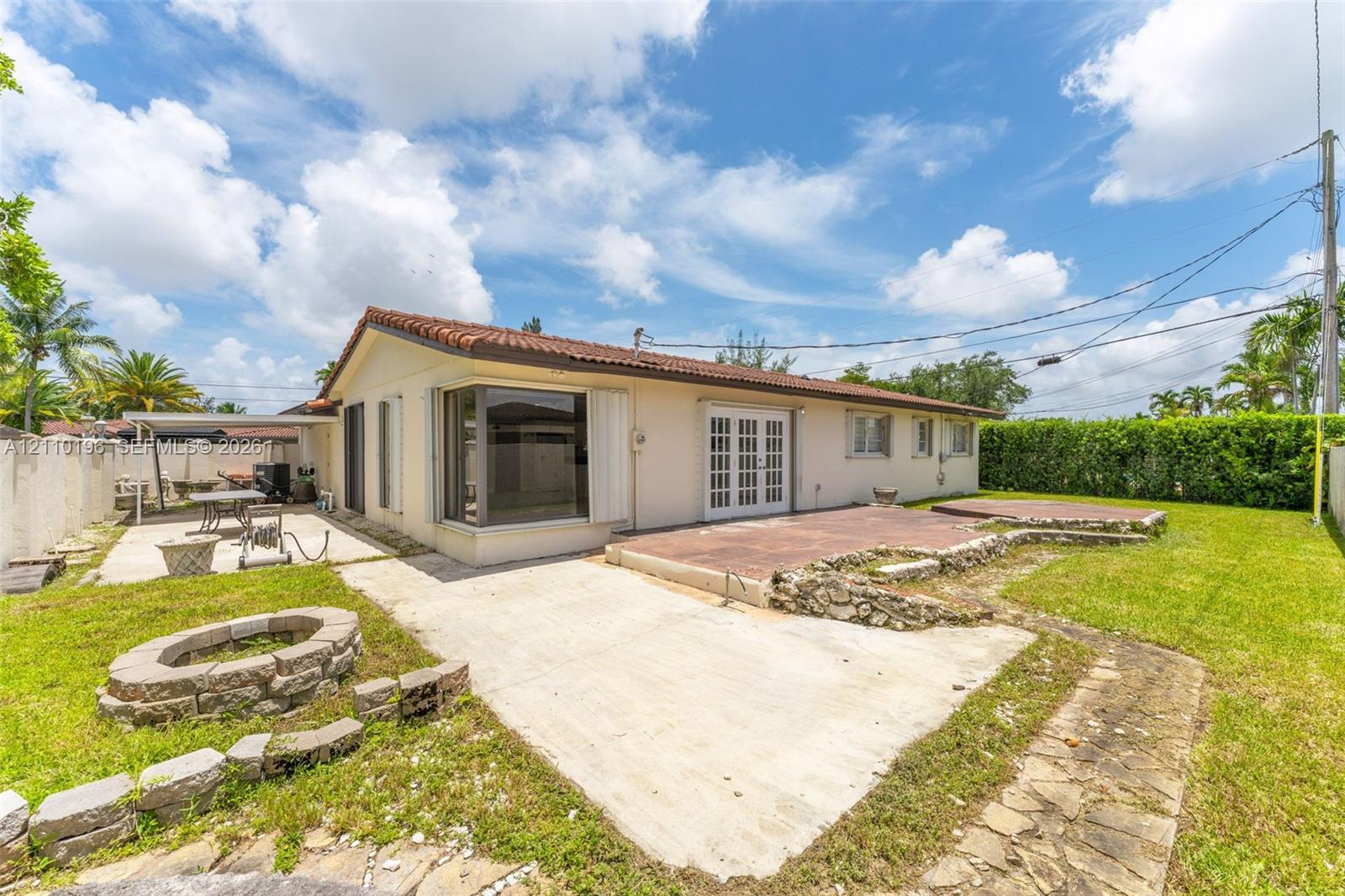 Exterior backyard featuring a concrete patio, stone-bordered fire pit, multi-level terrace, and covered side patio area