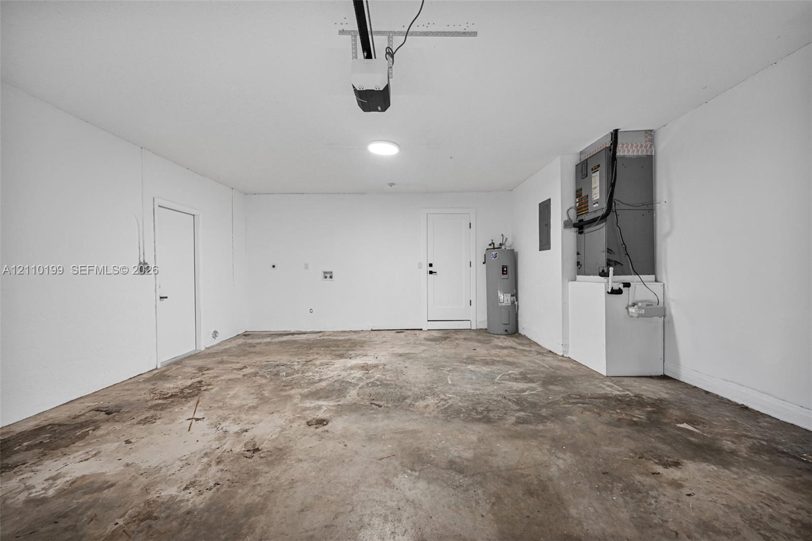 Garage interior featuring concrete flooring, installed HVAC air handler, built-in water heater, and automatic garage door opener
