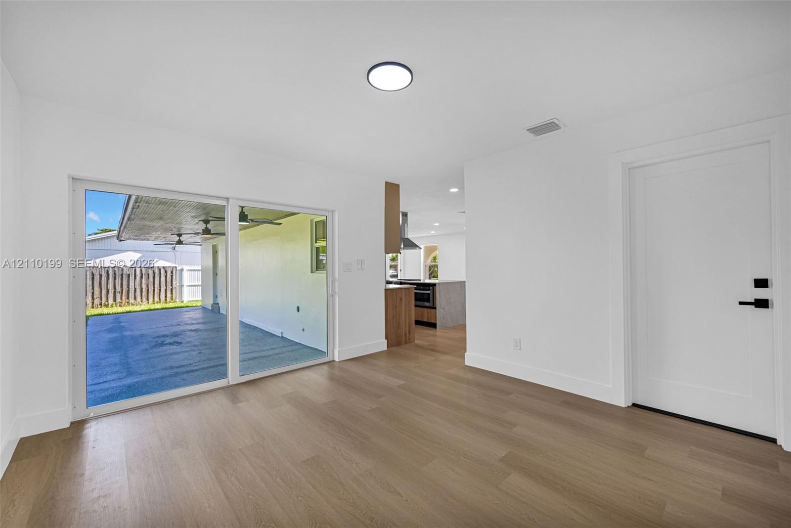 Interior featuring wood-finish flooring, sliding glass doors, and a solid-panel door with matte black hardware