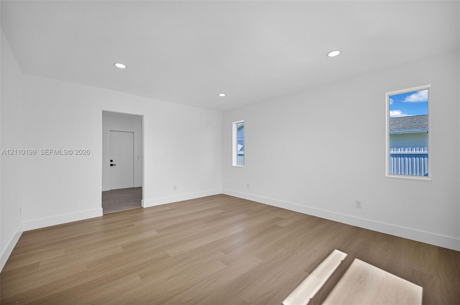 Neutral interior space featuring wood-finish flooring, recessed lighting, and dual vertical windows