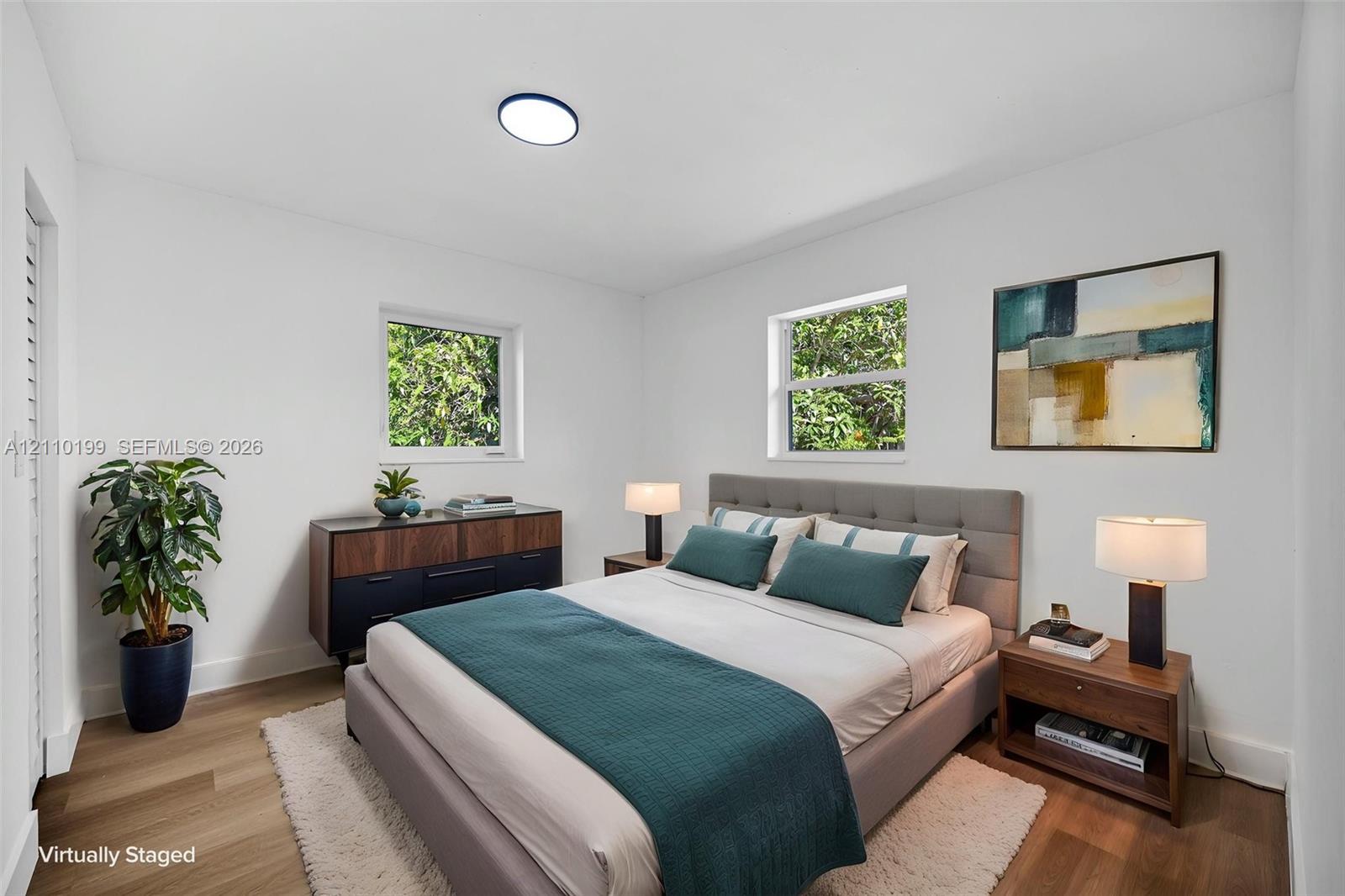Neutral interior featuring wood-finish flooring, two dual-pane windows, and a flush-mount ceiling light fixture