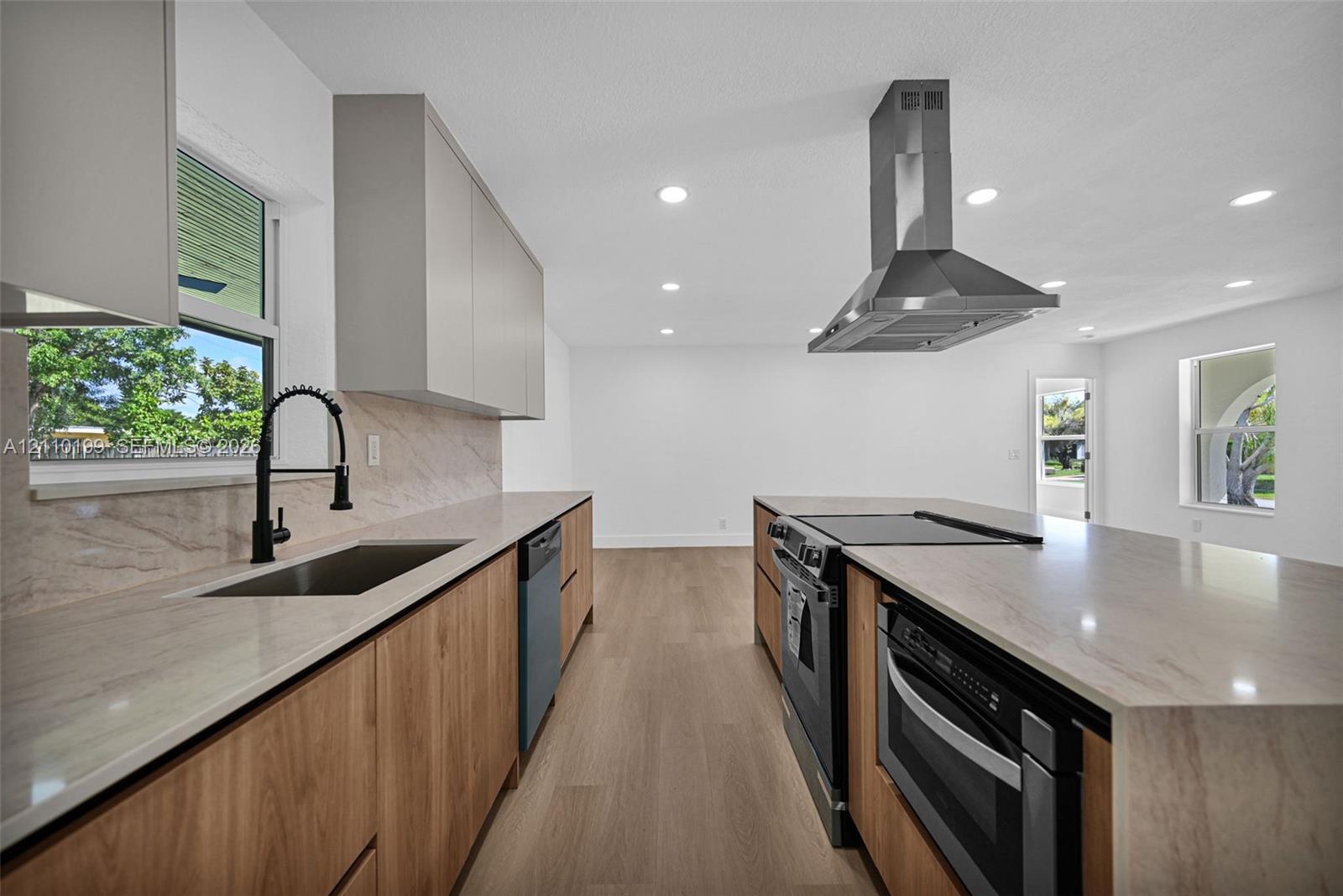 Kitchen featuring wood-finish lower cabinetry, stone-style countertops, matte black faucet, stainless steel range hood, and wood-finish flooring