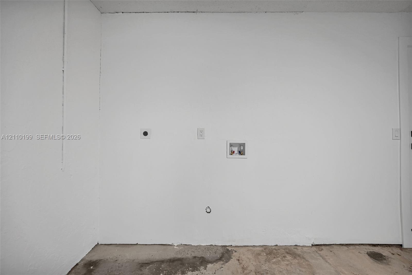 Dedicated utility area featuring washer and dryer hookups, recessed plumbing supply box, and electrical outlet