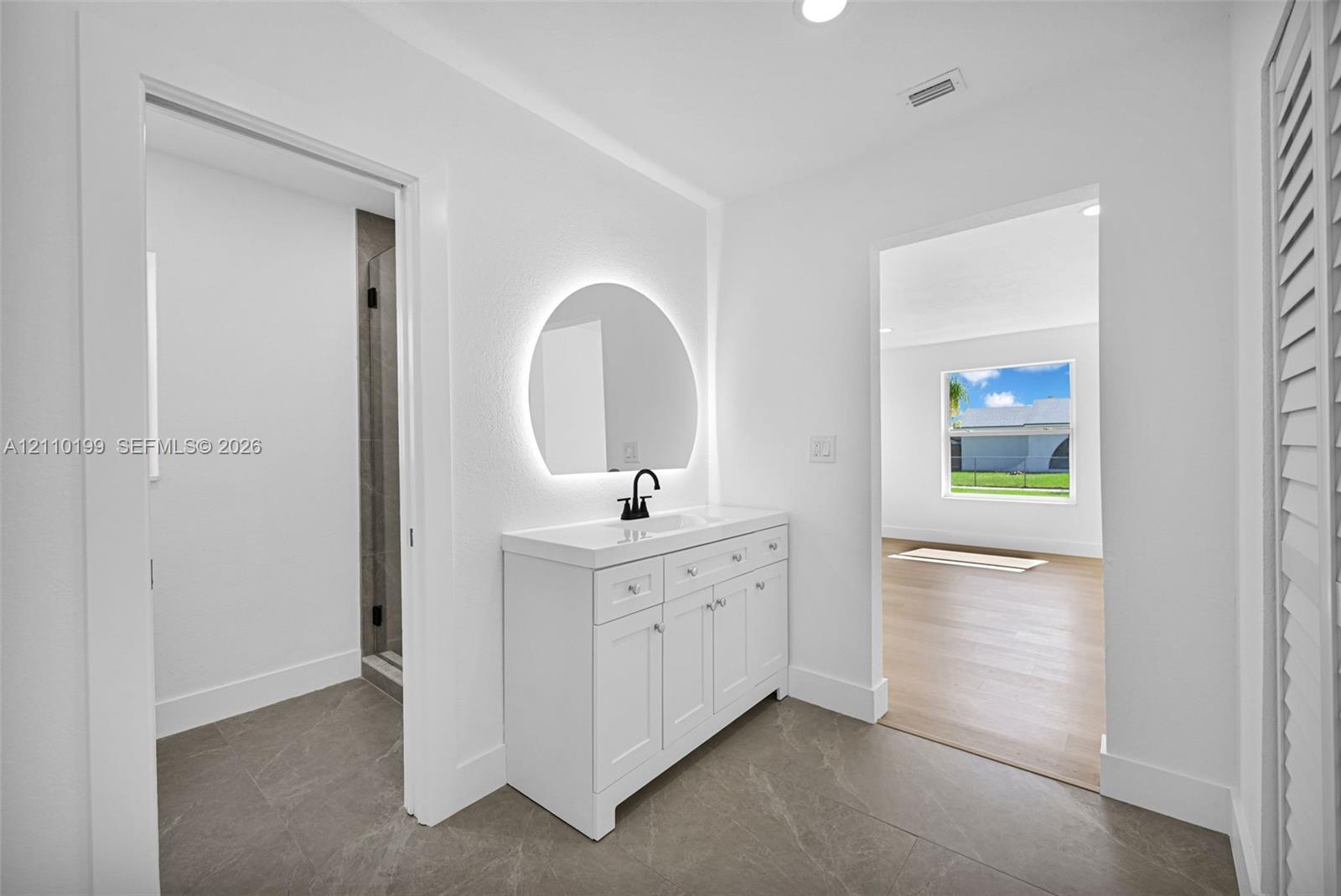 White vanity featuring a rectangular integrated sink, matte black faucet, and stone-finish tile flooring