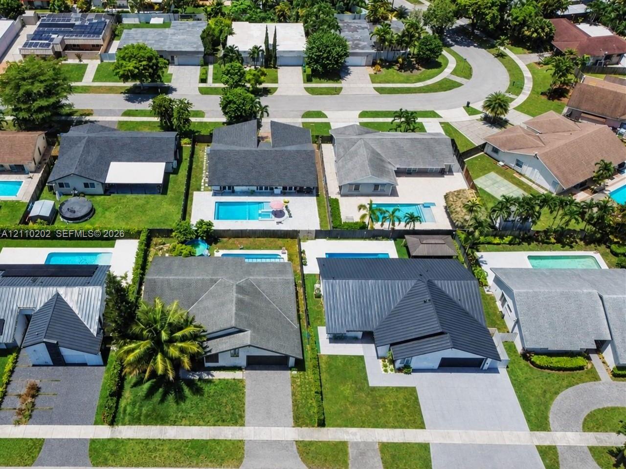 Aerial view of a residential neighborhood featuring single-story homes, private swimming pools, manicured lawns, and paved driveways