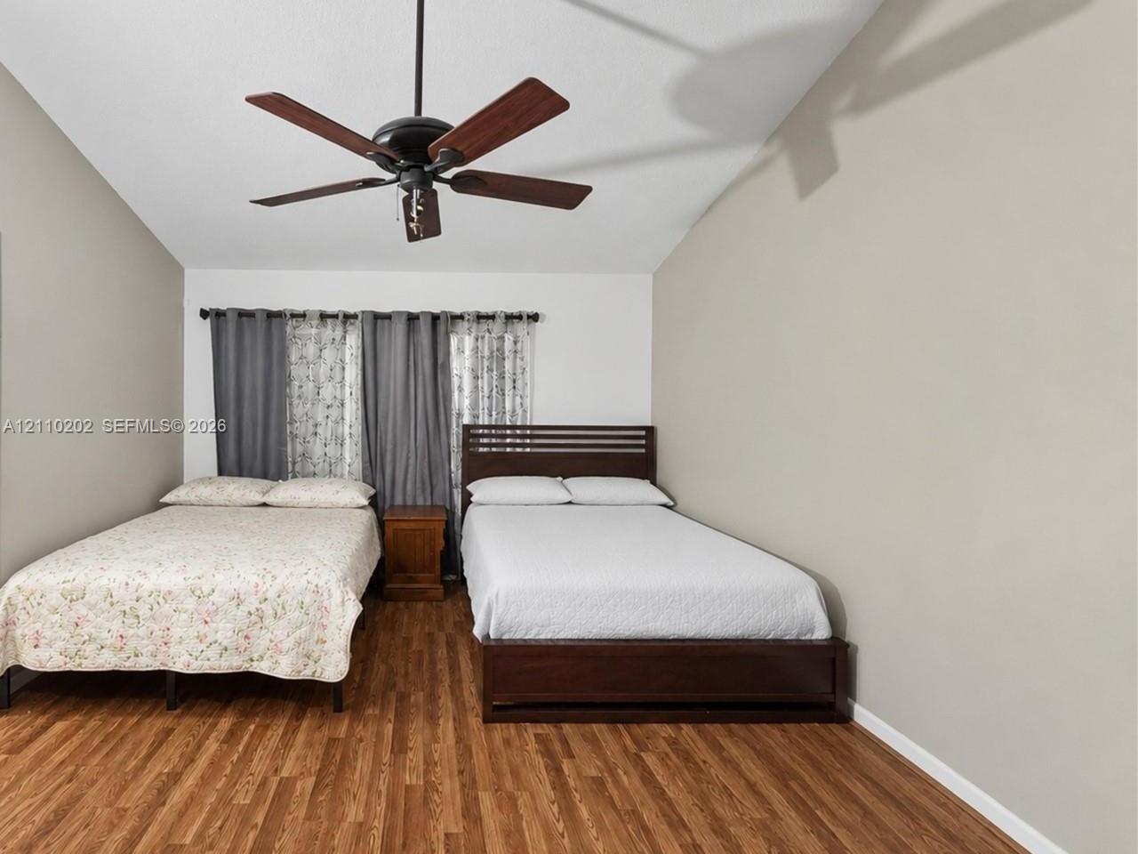 Vaulted ceiling featuring a central five-blade ceiling fan and wood-finish flooring