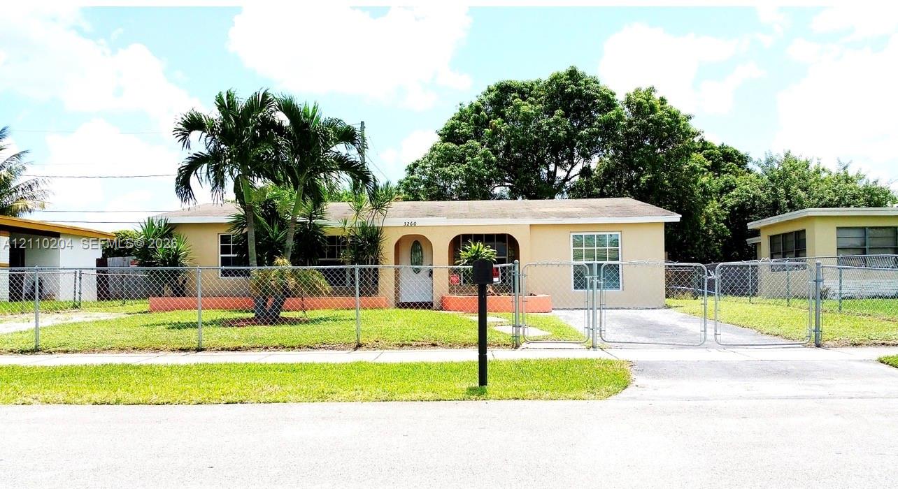 Single-story residence featuring an arched entryway, concrete driveway, and chain-link perimeter fencing Single-story residence featuring an arched entryway, concrete driveway, and chain-link perimeter fencing