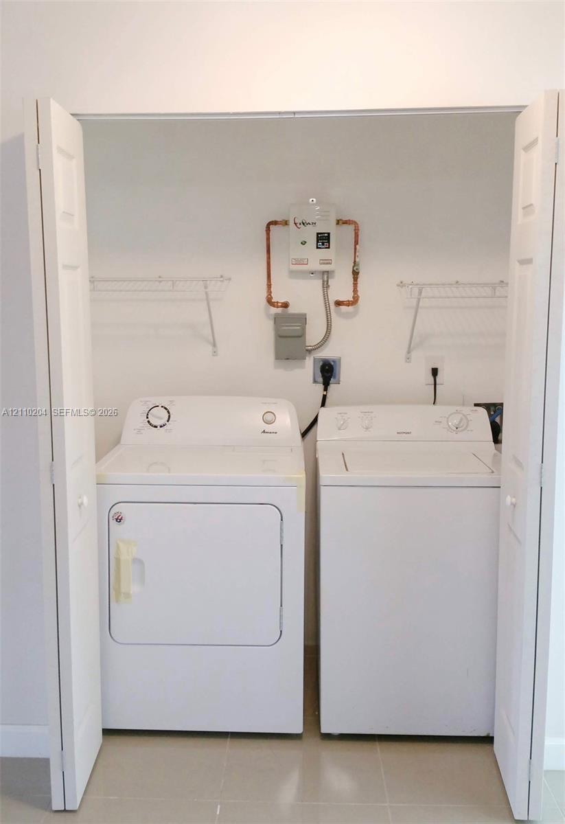 Laundry closet featuring bi-fold doors, wall-mounted wire shelving, and an on-demand tankless water heater