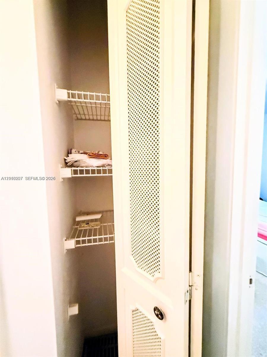 Storage closet featuring bi-fold doors with louvered panels and tiered wire shelving