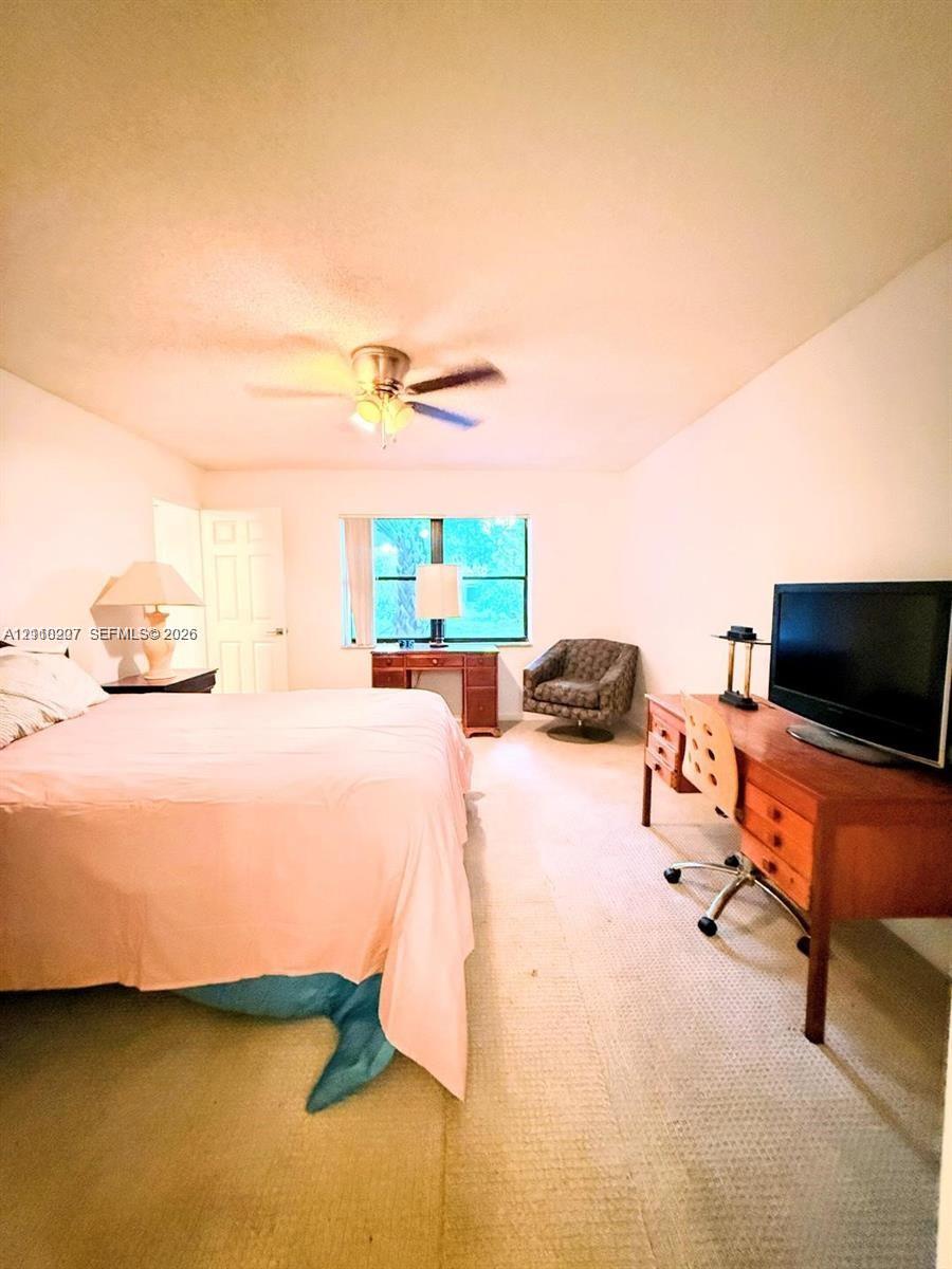 Room featuring wall-to-wall carpeting, a multi-blade ceiling fan with integrated lighting, and a single-pane window