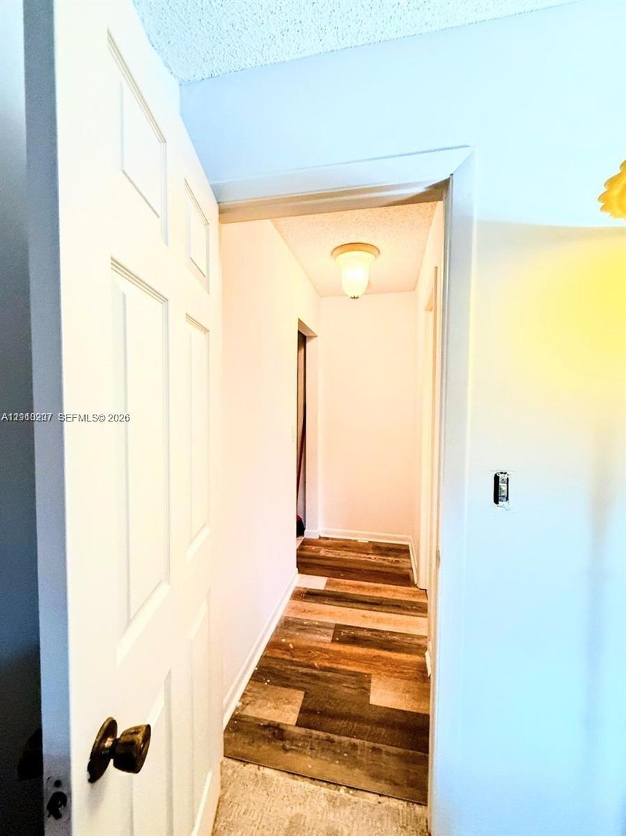 Six-panel interior door with dark metal hardware, flush-mount ceiling lighting, and wood-finish flooring