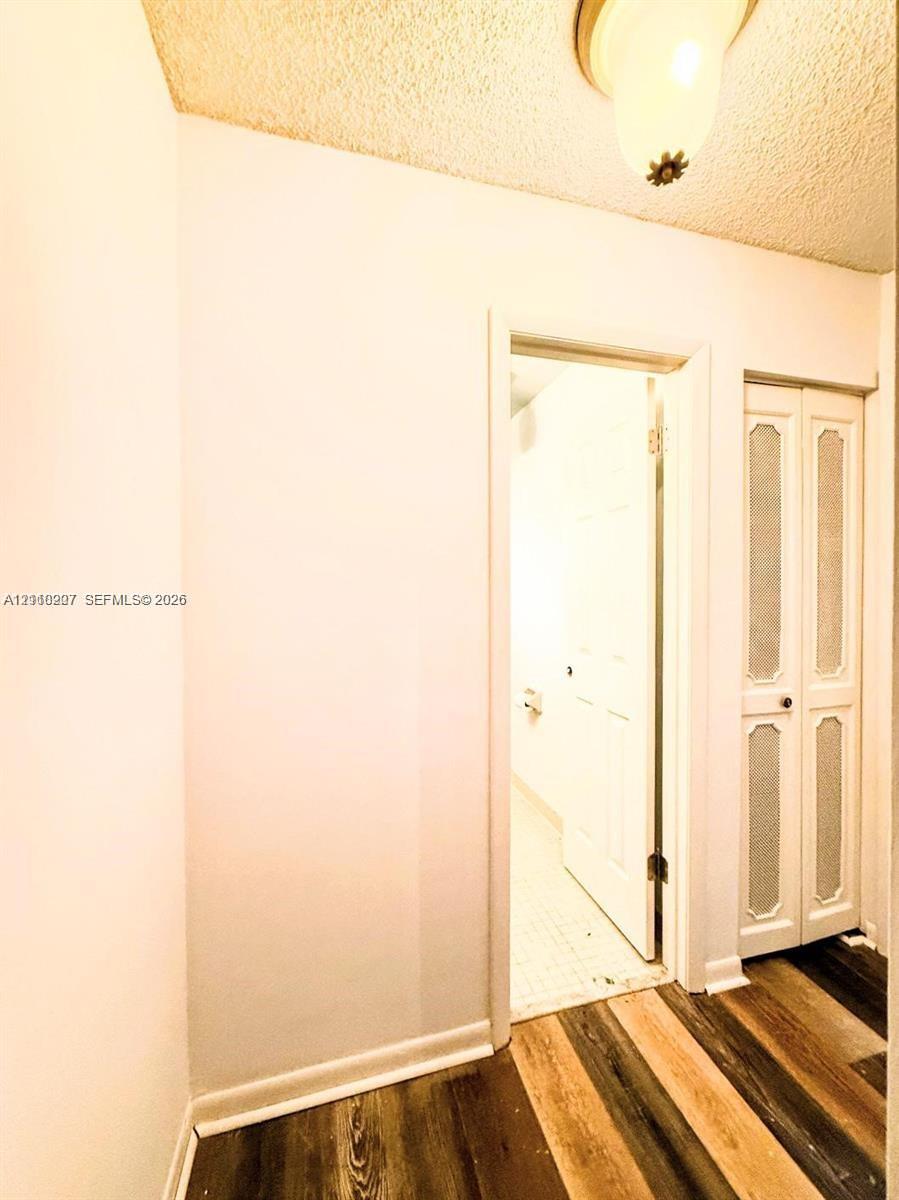 Wood-finish flooring, bi-fold closet doors with textured glass panel inserts, and ceiling-mounted dome lighting