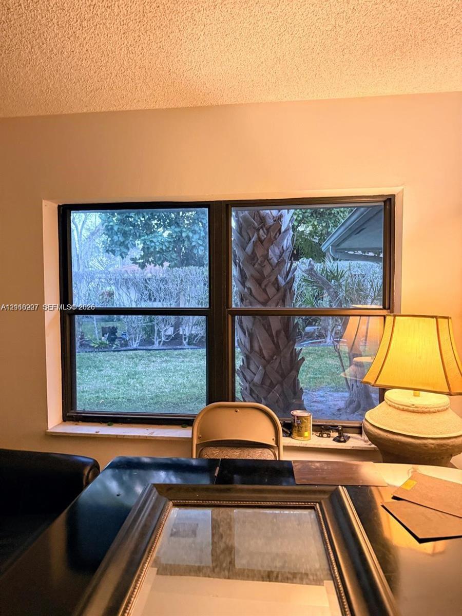 Double-pane window featuring a dark frame and a ledge overlooking an outdoor area with mature palm trees and greenery