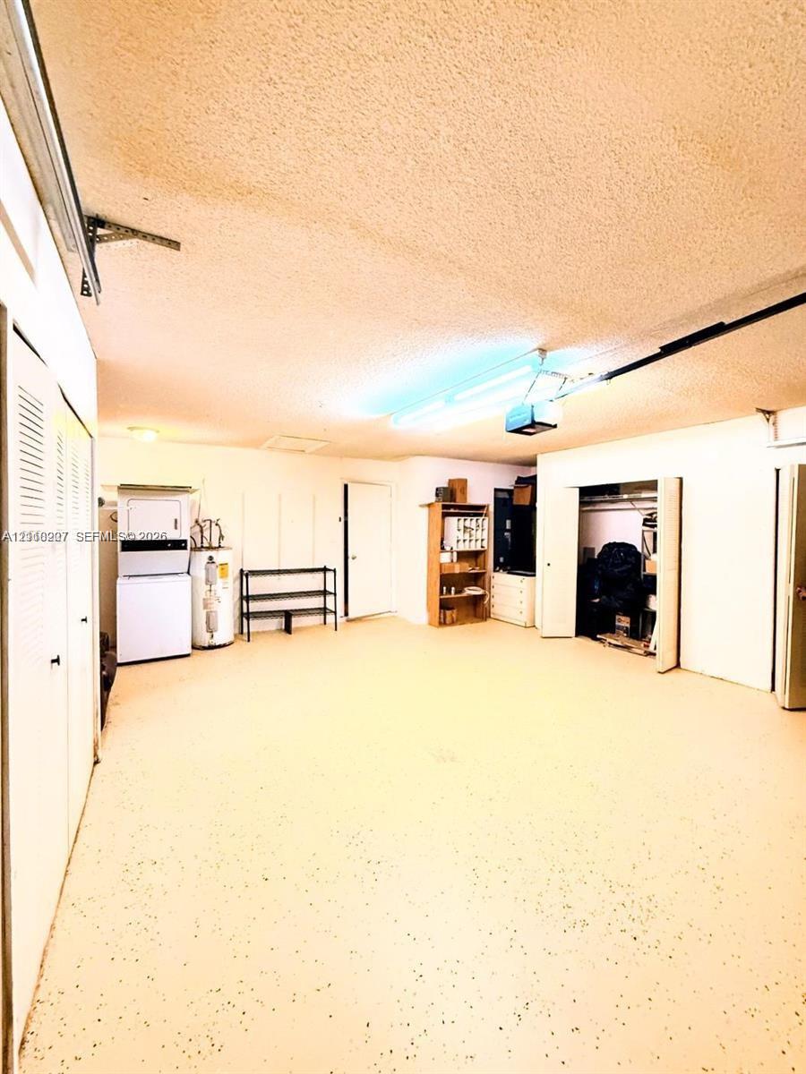 Garage featuring an epoxy-coated floor, integrated laundry hookups, built-in storage shelving, and overhead fluorescent lighting