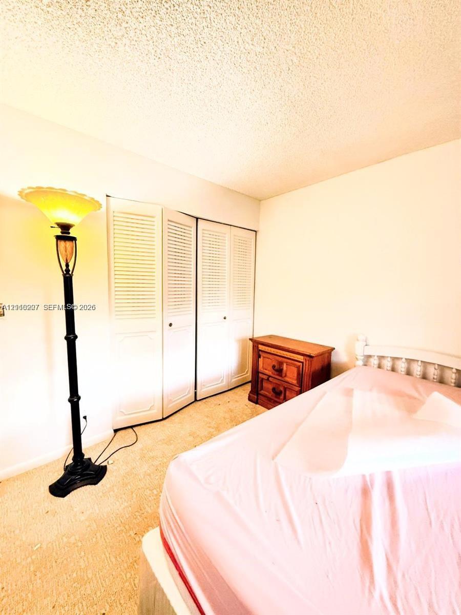 Room interior featuring floor-to-ceiling white louvered bifold closet doors and wall-to-wall carpeting