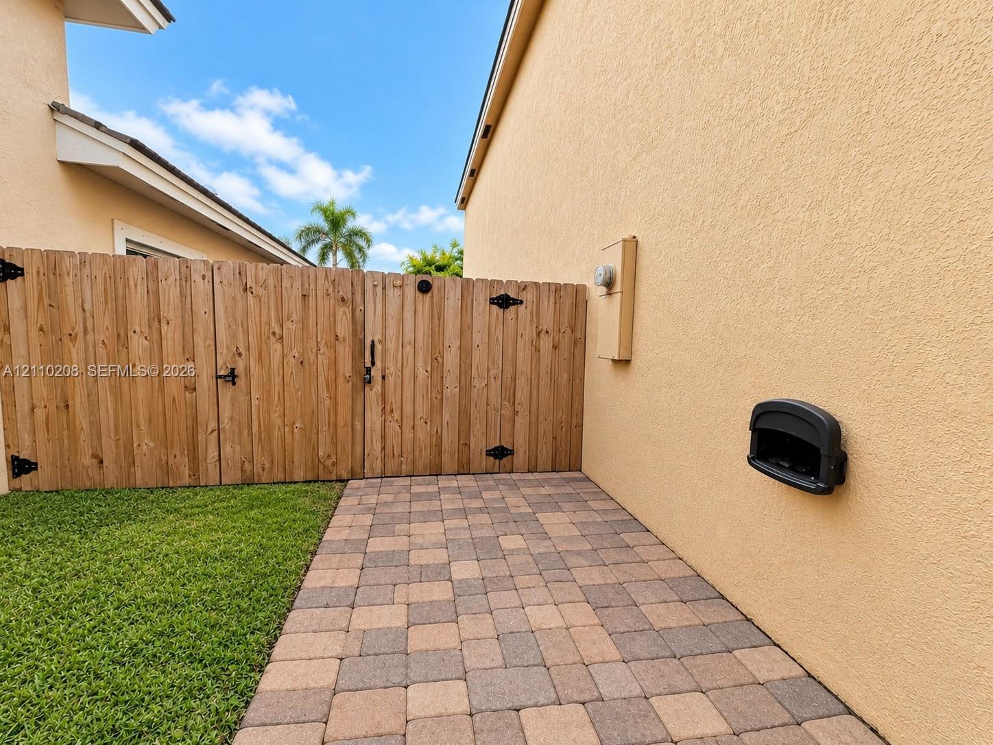 Side yard featuring a paver patio, wood-finish privacy fencing, and a manicured lawn