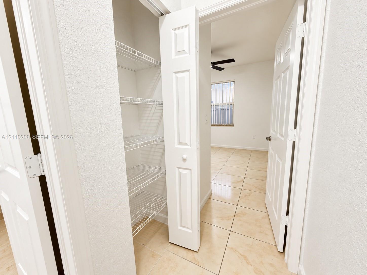 Built-in storage closet with multi-tier wire shelving, finished with ceramic tile flooring and white paneled doors