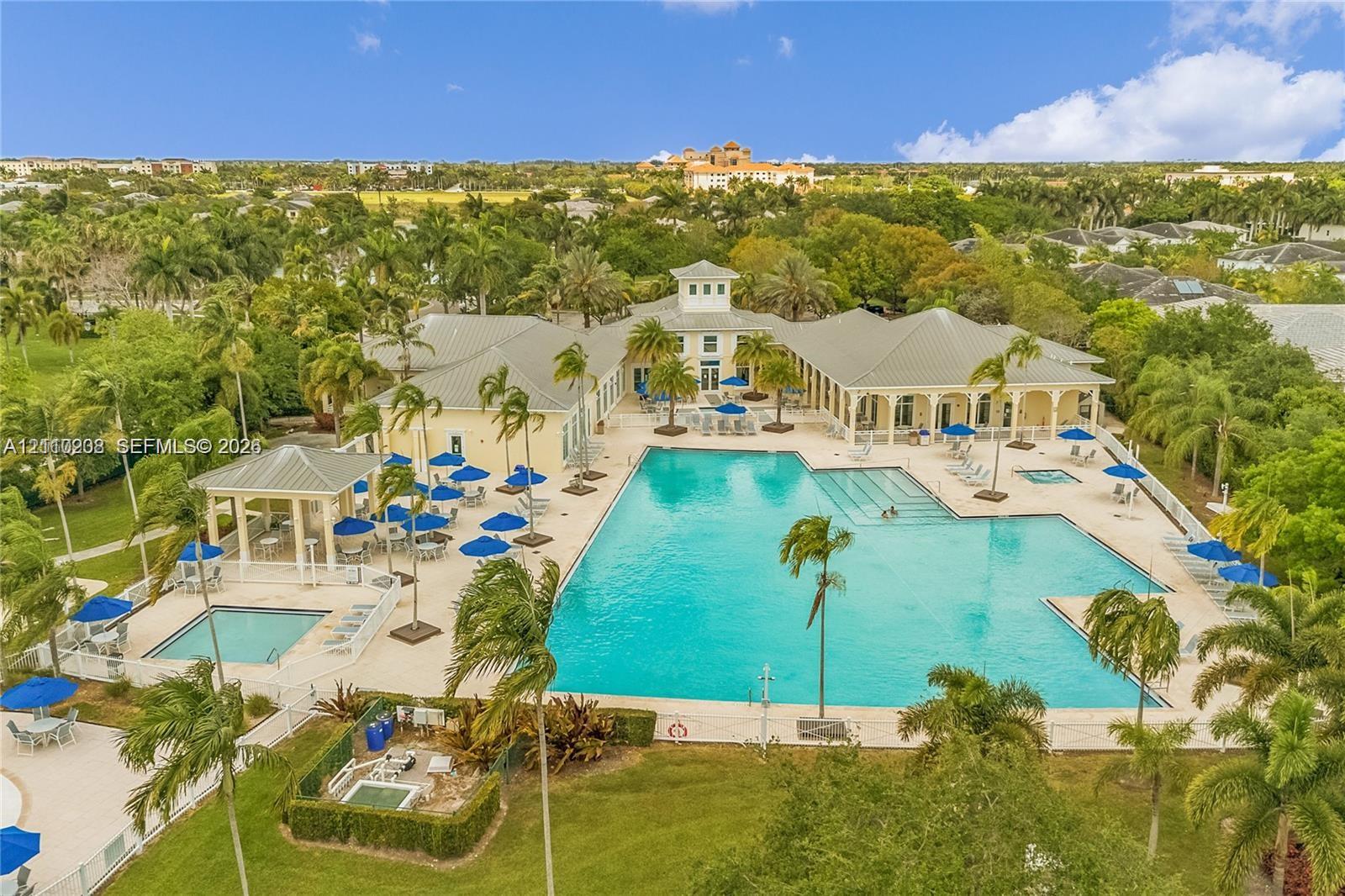Large-scale swimming pool featuring a lap lane, integrated spa, covered pavilion, and surrounding stone-paver deck
