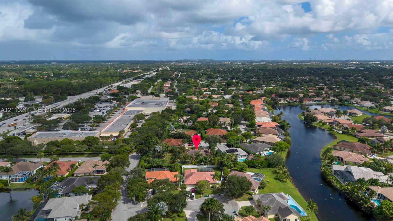 Aerial perspective of a residential community featuring extensive mature canopy trees, winding neighborhood roads, and proximity to a waterway