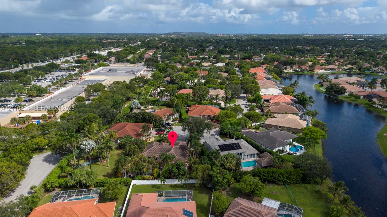 Aerial perspective of a residential property featuring a tiled roof, mature landscaping, palm trees, and a spacious lot