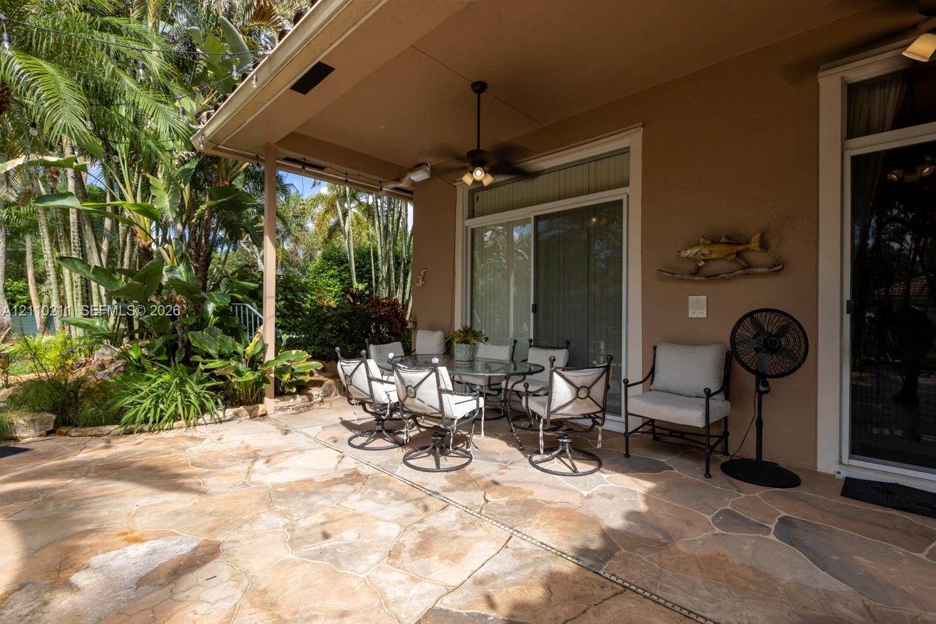 Covered patio featuring natural stone flooring, recessed lighting, and a ceiling-mounted fan with integrated light fixture