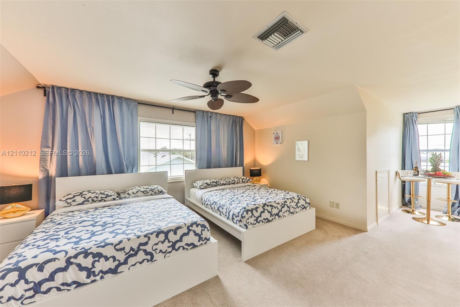 Vaulted ceiling featuring a central multi-blade ceiling fan and wall-to-wall carpeting