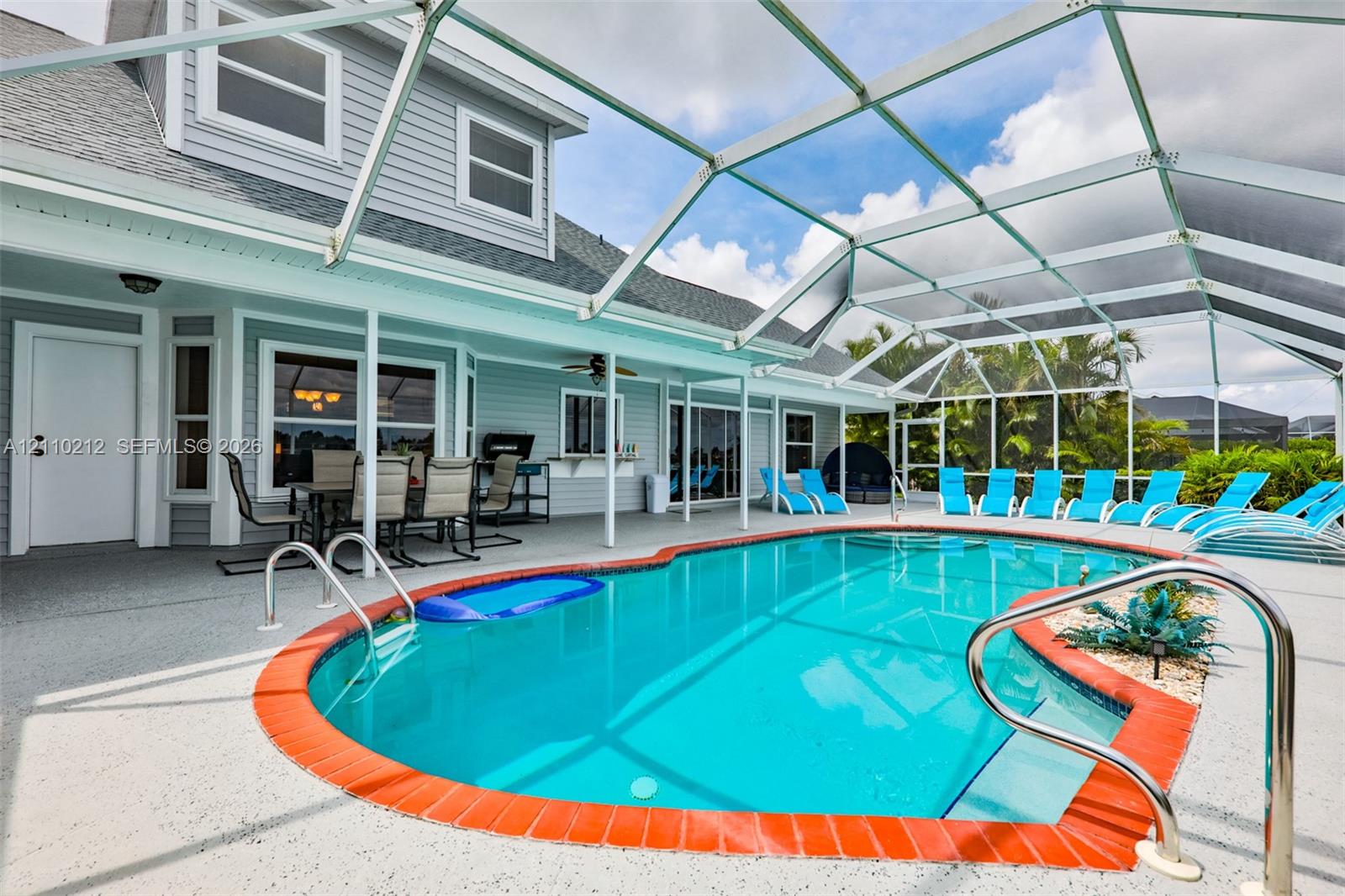 Screen-enclosed patio with a concrete deck, kidney-shaped swimming pool with terracotta-style brick coping, built-in pass-through window, and lap siding exterior