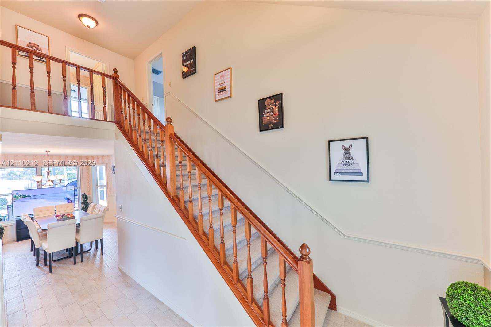 Staircase featuring wood railings and balusters, vaulted ceilings, and light-toned tile flooring