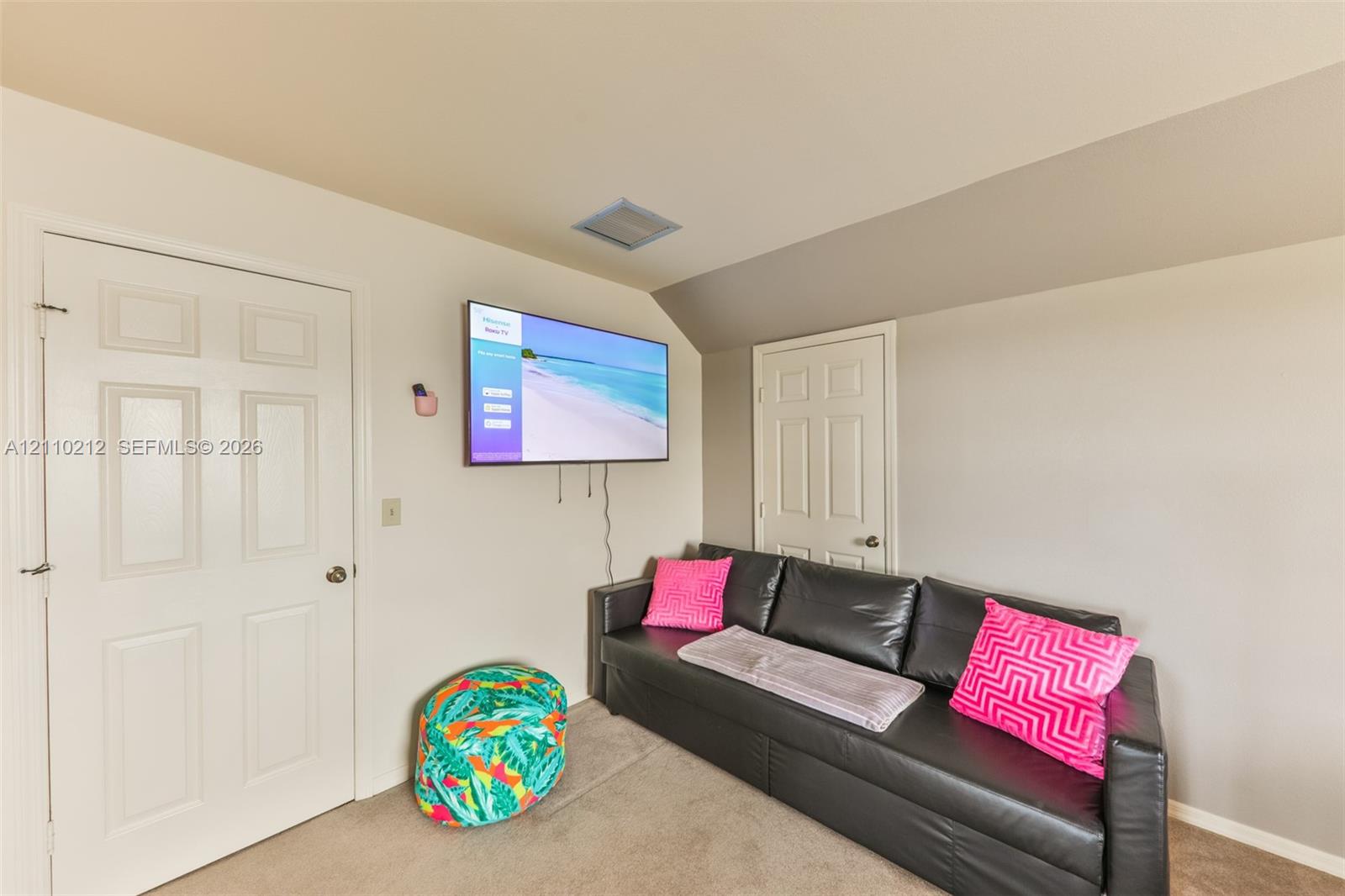 Room featuring a neutral wall palette, two solid-core interior doors, wall-to-wall carpeting, and an angled ceiling