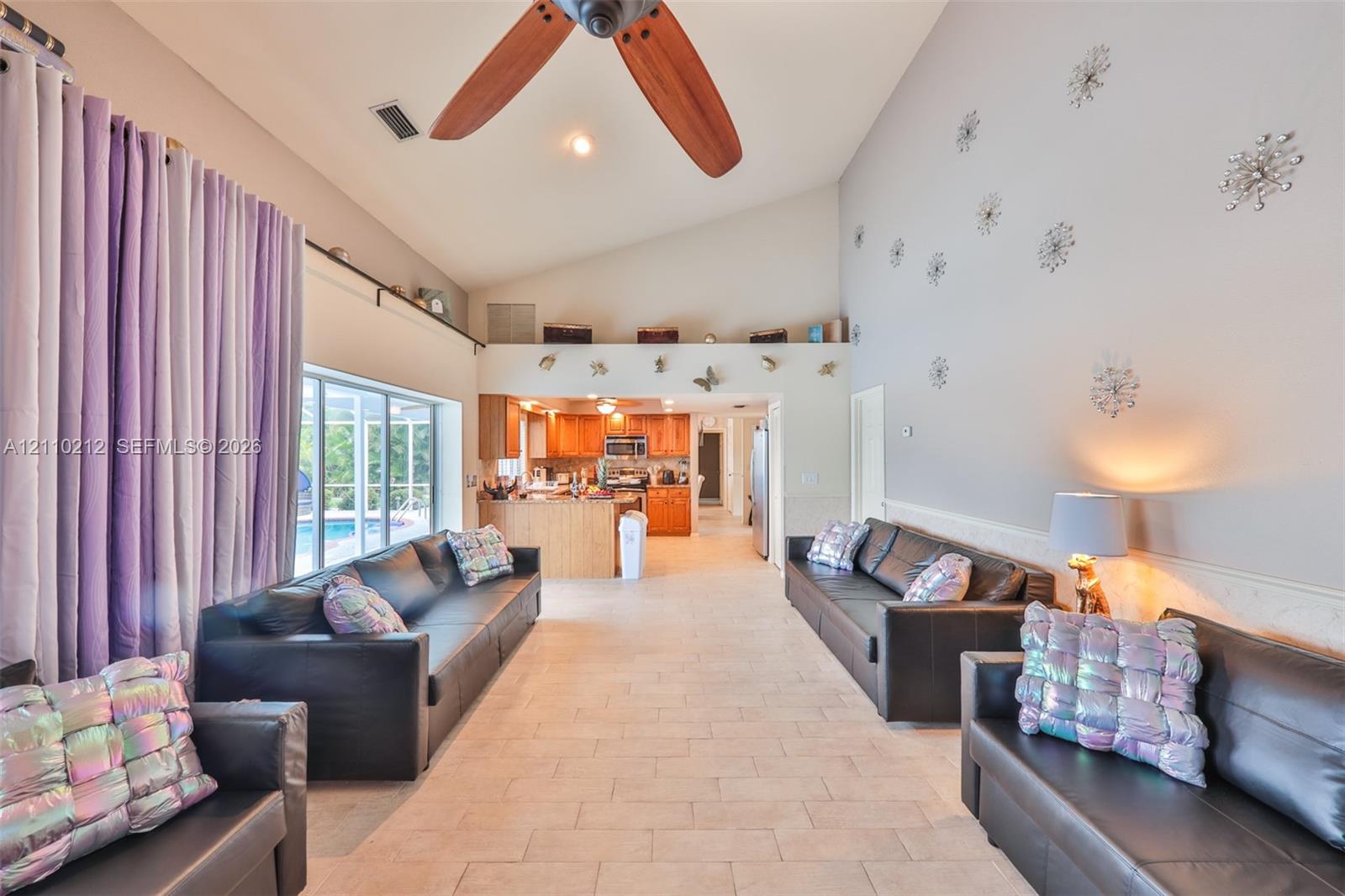 Vaulted ceilings, tile flooring, and a ceiling fan with wooden blades