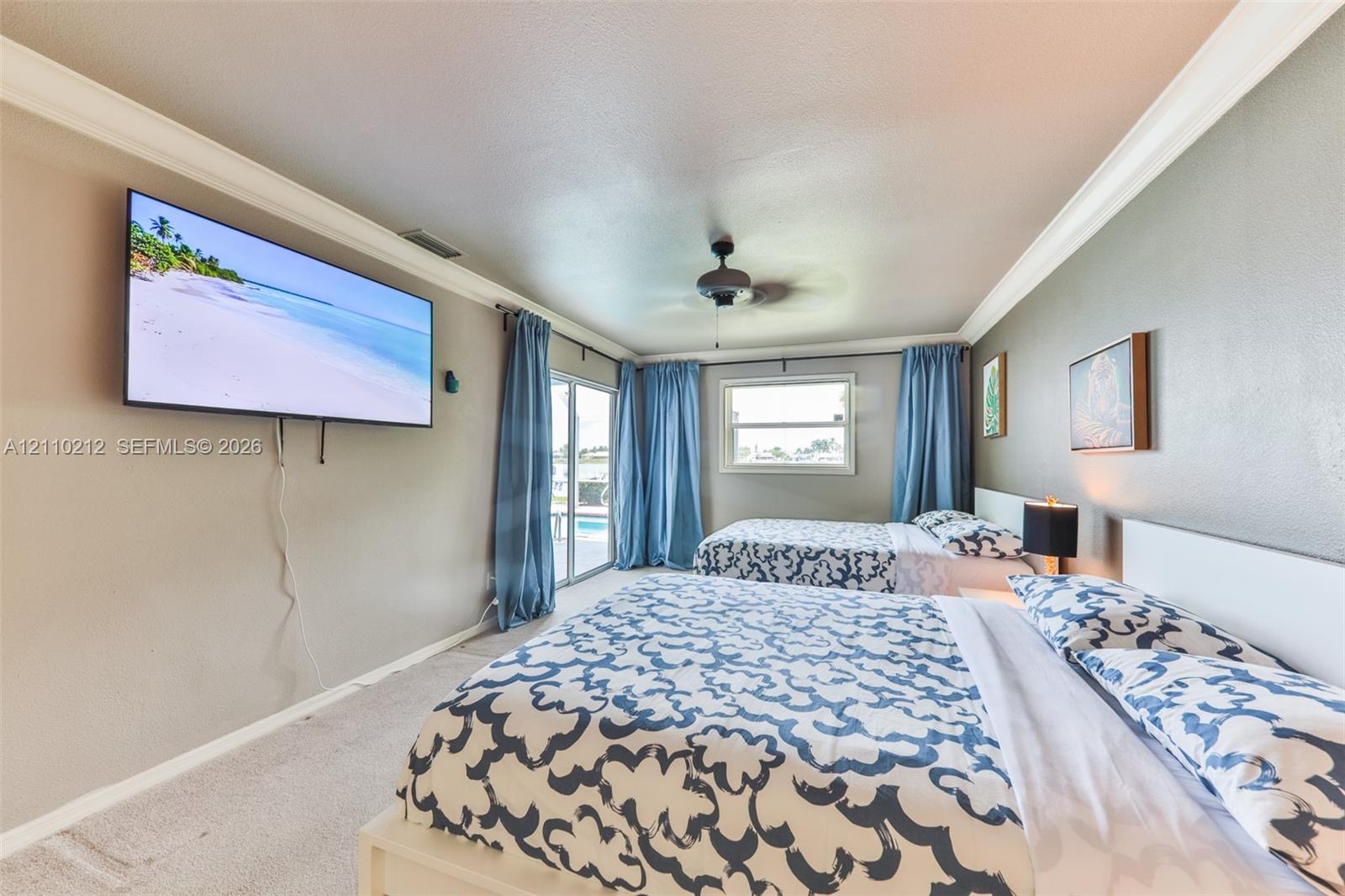 Neutral-tone interior featuring crown molding, a ceiling fan, and sliding glass doors