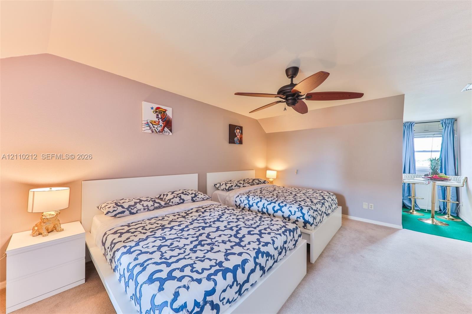 Vaulted ceiling with a central multi-blade ceiling fan and wall-to-wall carpeting