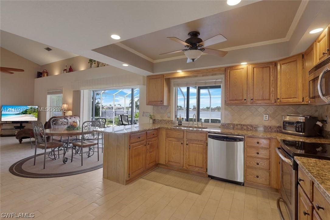 Kitchen featuring wood cabinetry, stone-finish countertops, stainless steel dishwasher, tile flooring, and a tray ceiling