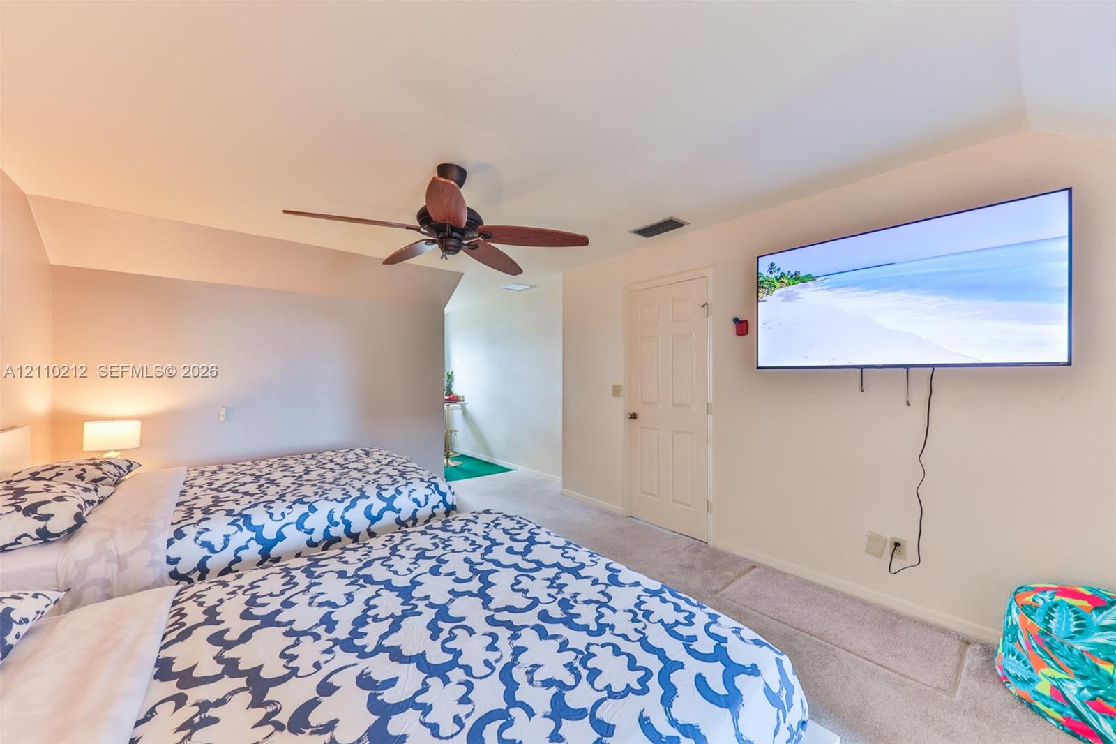Interior space featuring vaulted ceilings, neutral-toned wall paint, wall-to-wall carpeting, a ceiling fan with integrated lighting, and a six-panel interior door