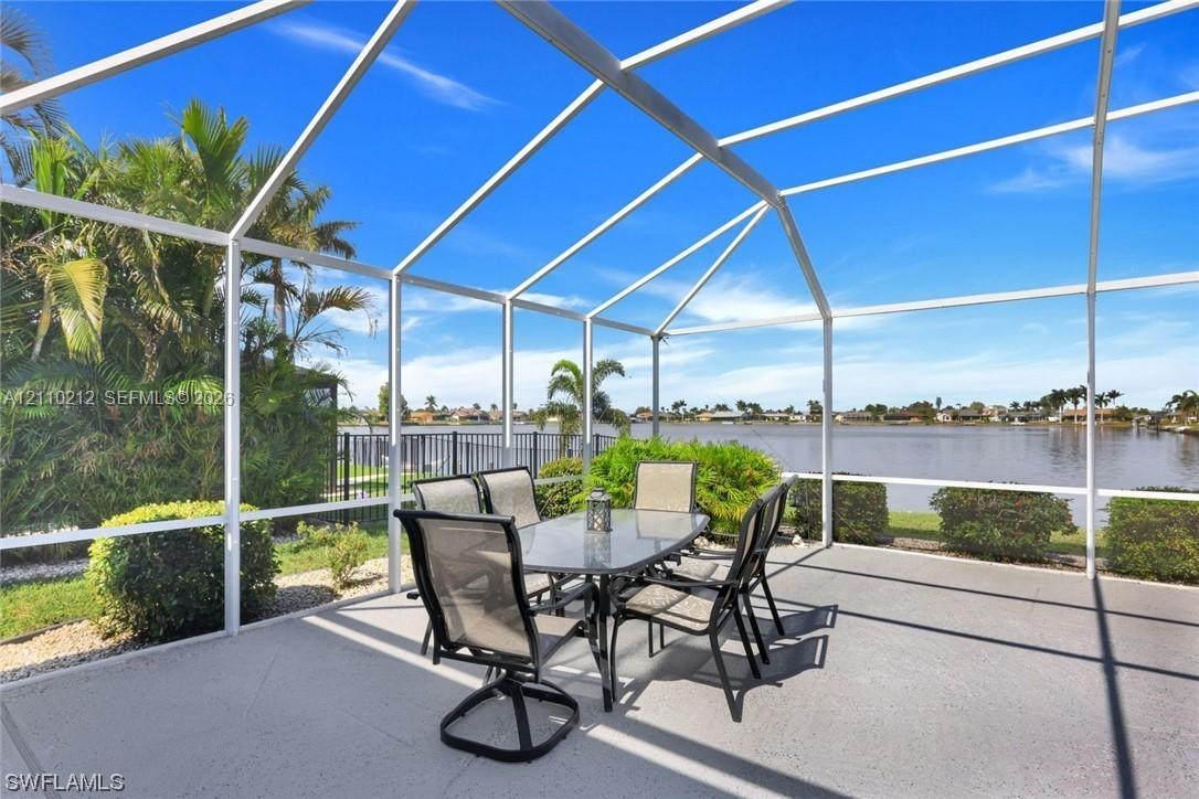 Screened-in lanai featuring a concrete deck and a metal frame enclosure, overlooking a lake with mature landscaping
