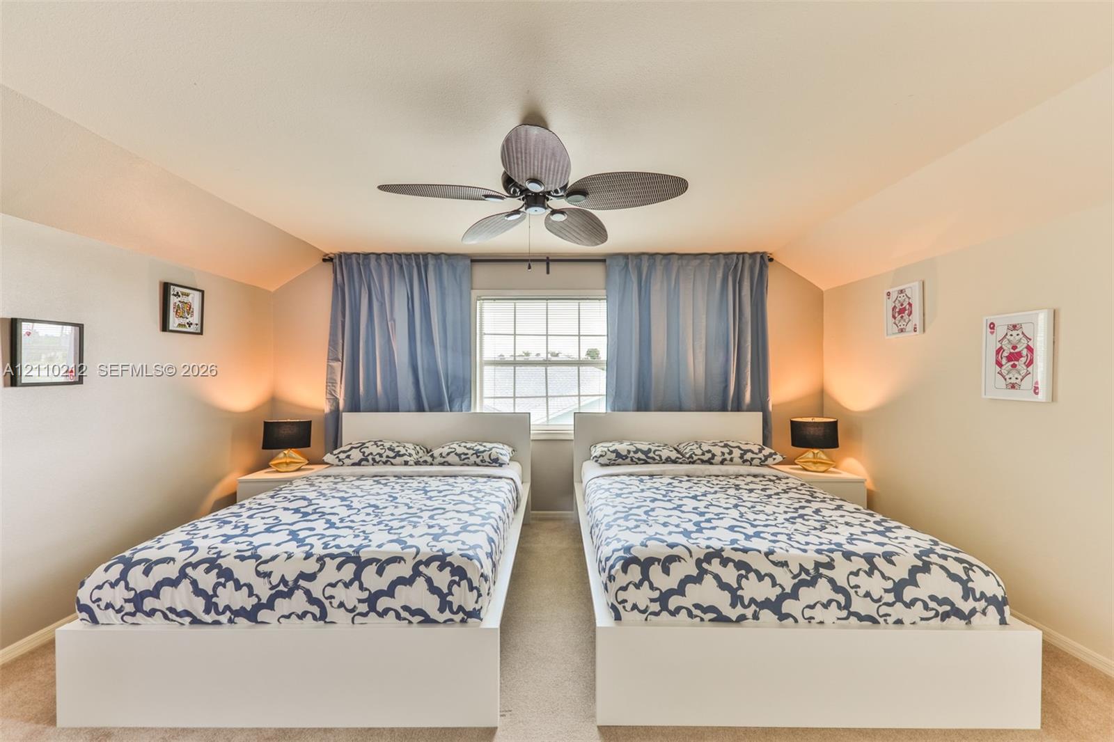 Vaulted ceiling featuring a central multi-blade ceiling fan and a single window with exterior light filtration