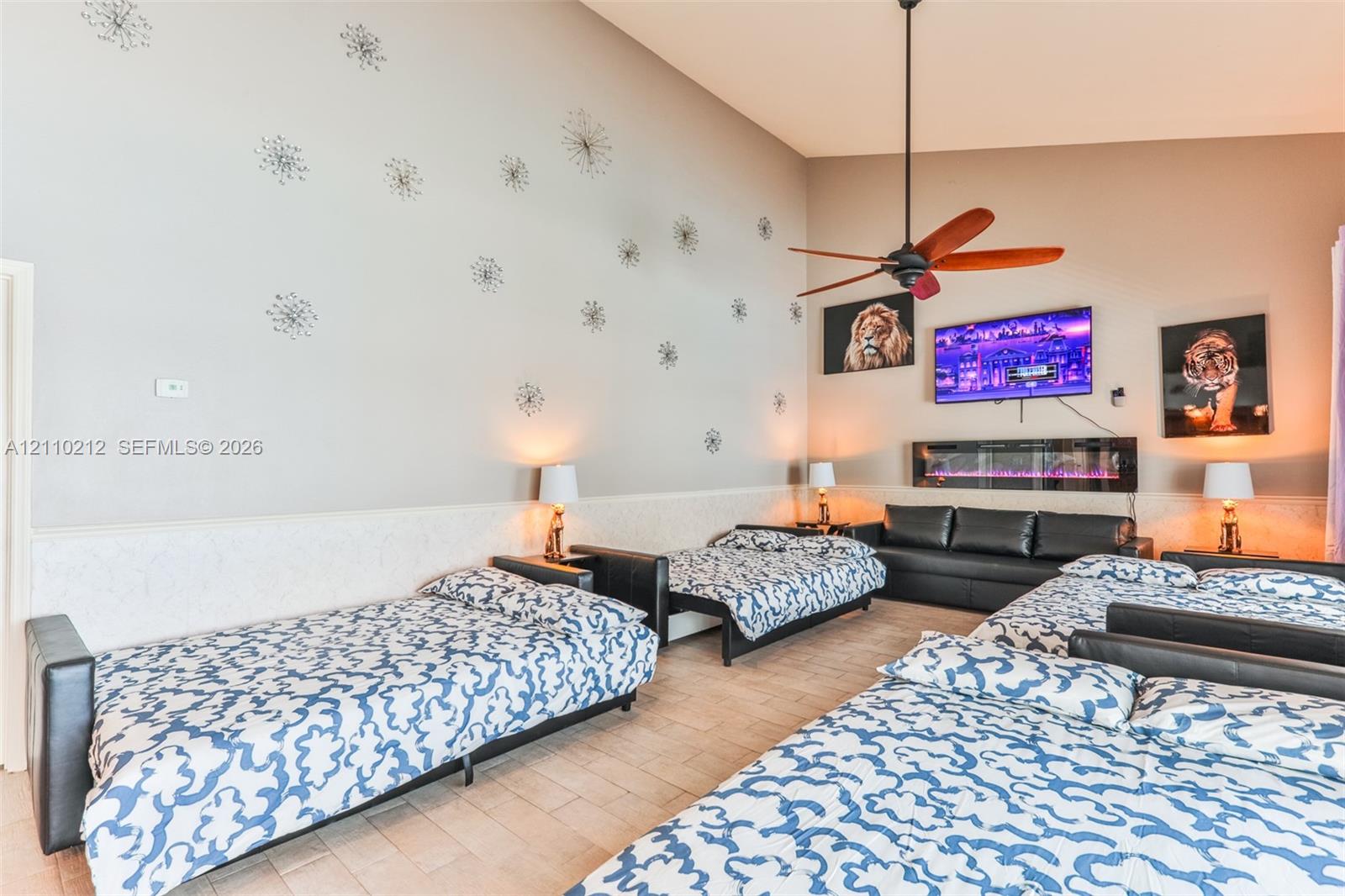 Vaulted ceilings featuring a central ceiling fan and a wall-mounted electric fireplace