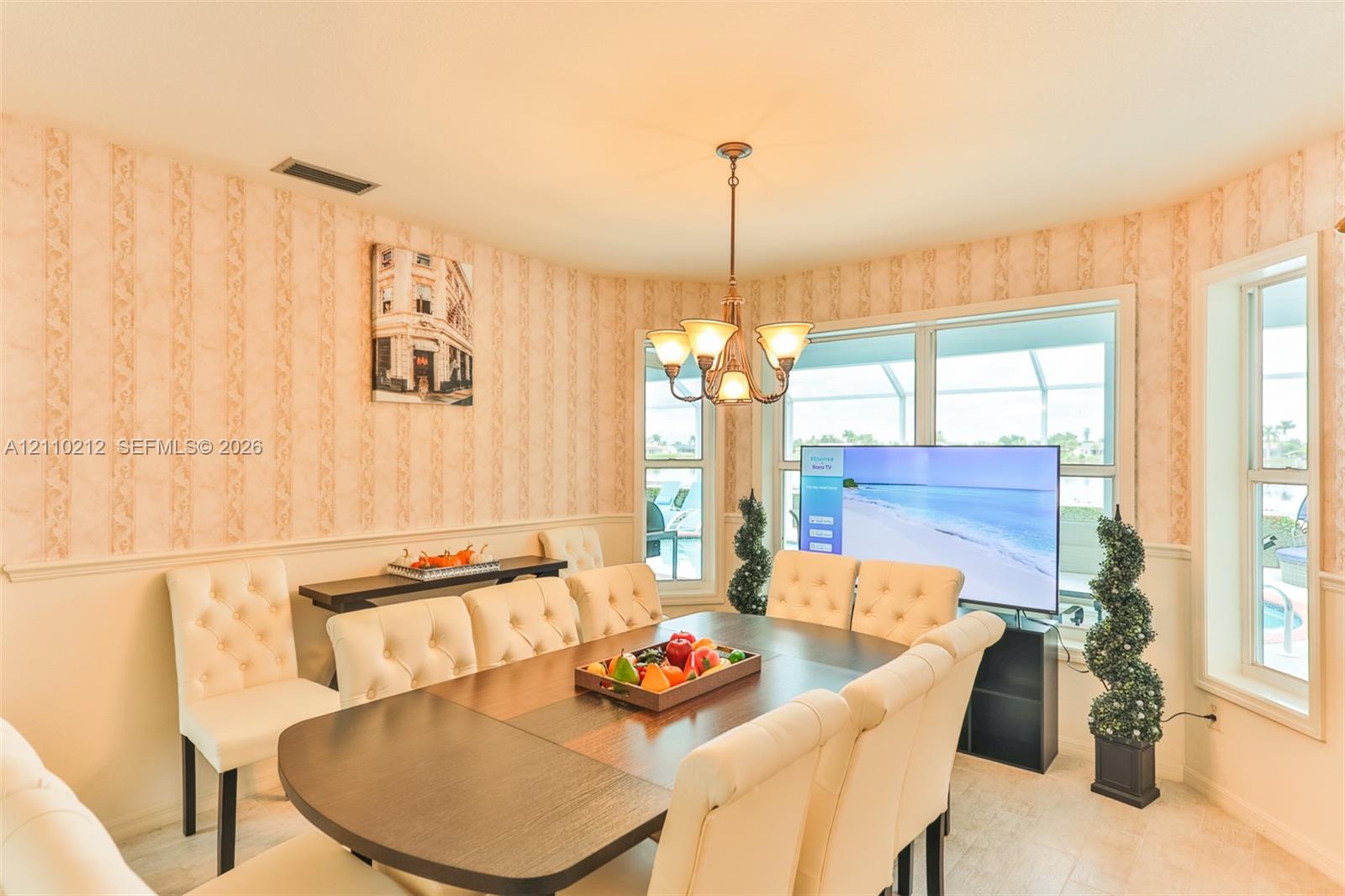 Dining area featuring expansive bay windows, crown-style metal chandelier, and chair rail molding