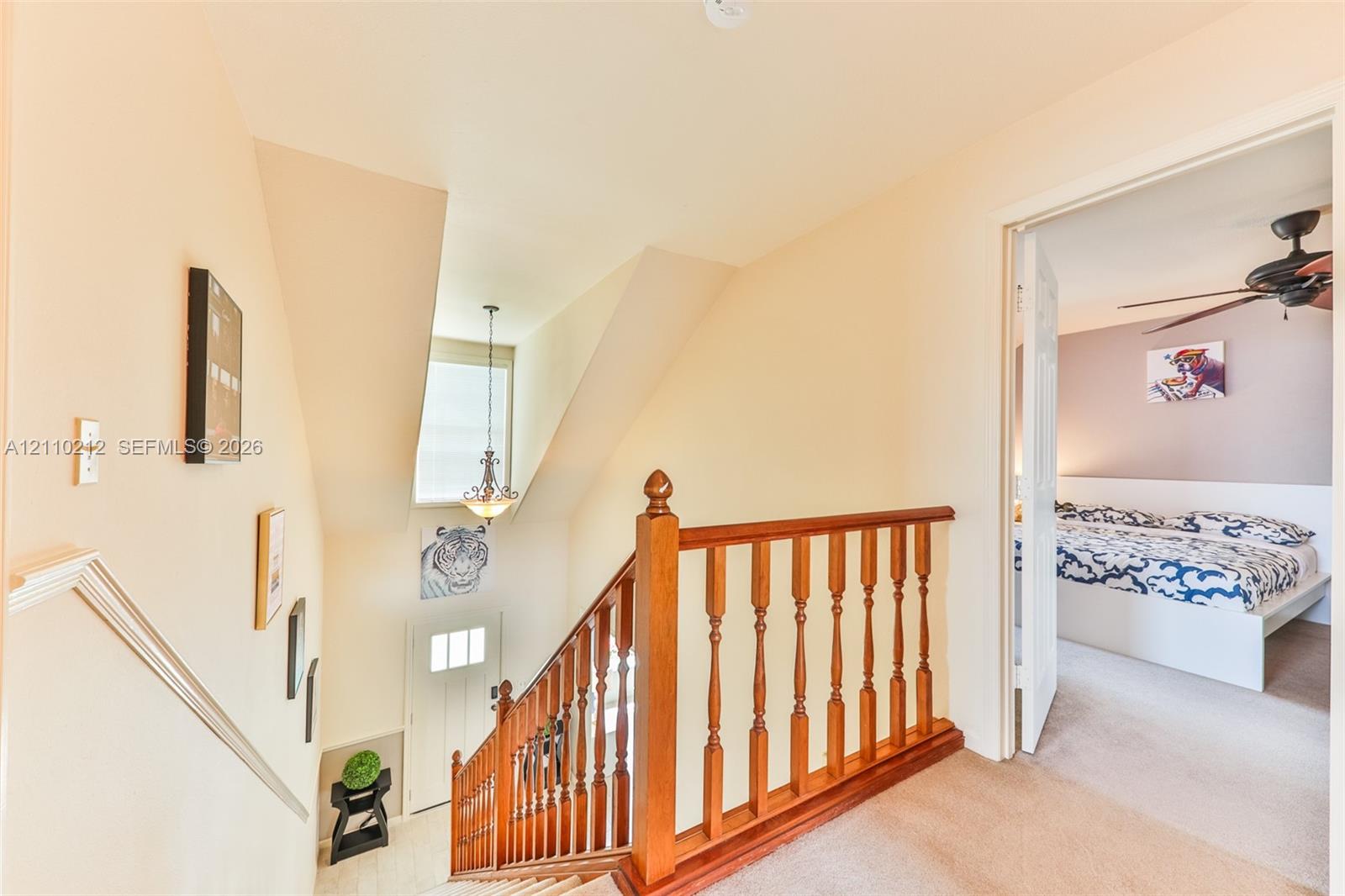 Staircase featuring wood railings and balusters, tiered landing, suspended pendant light fixture, and neutral wall color