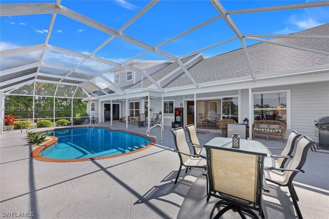 Screened-in patio featuring a concrete deck and a kidney-shaped pool with a decorative brick border