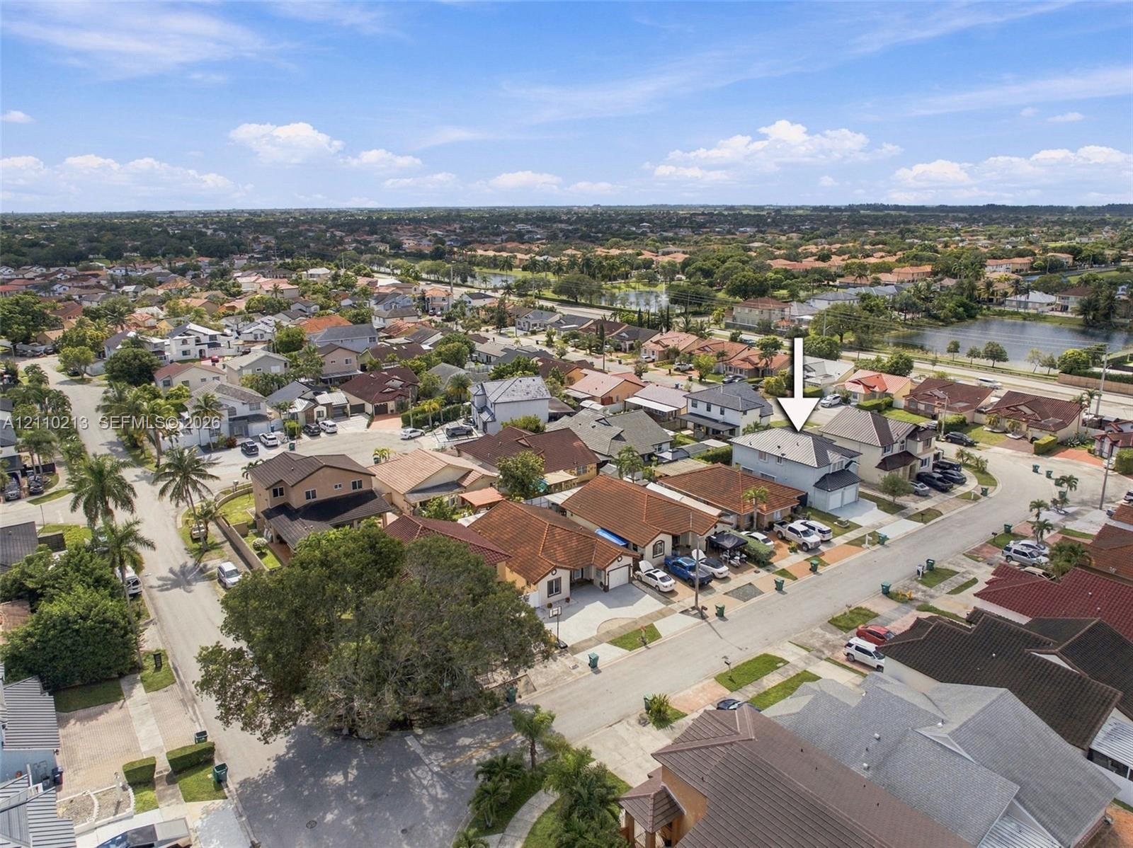 Aerial perspective of a two-story residence featuring a multi-pitched shingle roof, attached garage, and paved driveway within a suburban residential community