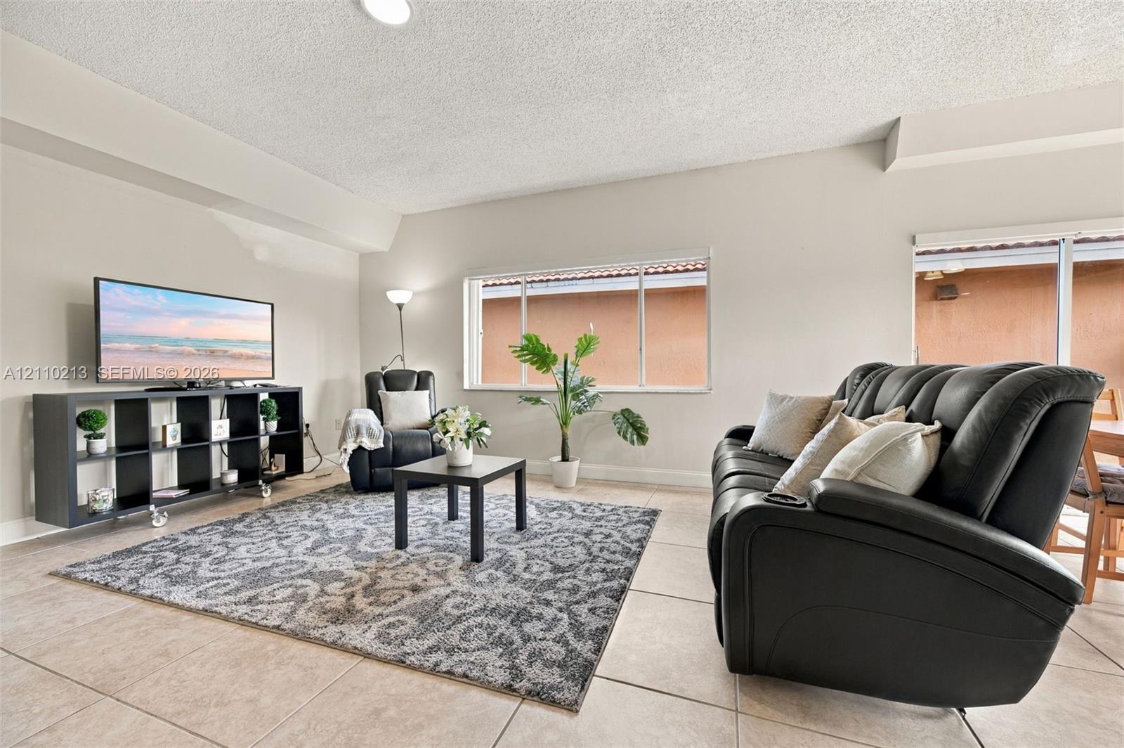Neutral-toned interior space featuring light-colored ceramic tile flooring, horizontal sliding windows, and a sliding glass door providing access to the exterior