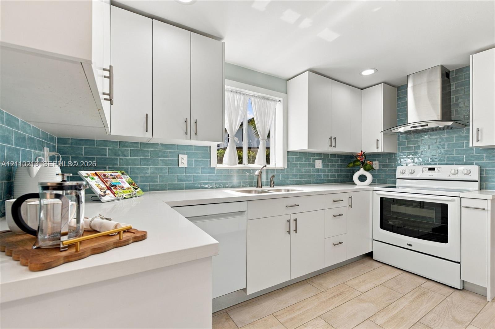 Kitchen featuring white cabinetry, solid-surface countertops, blue subway tile backsplash, stainless steel range hood, and wood-finish flooring