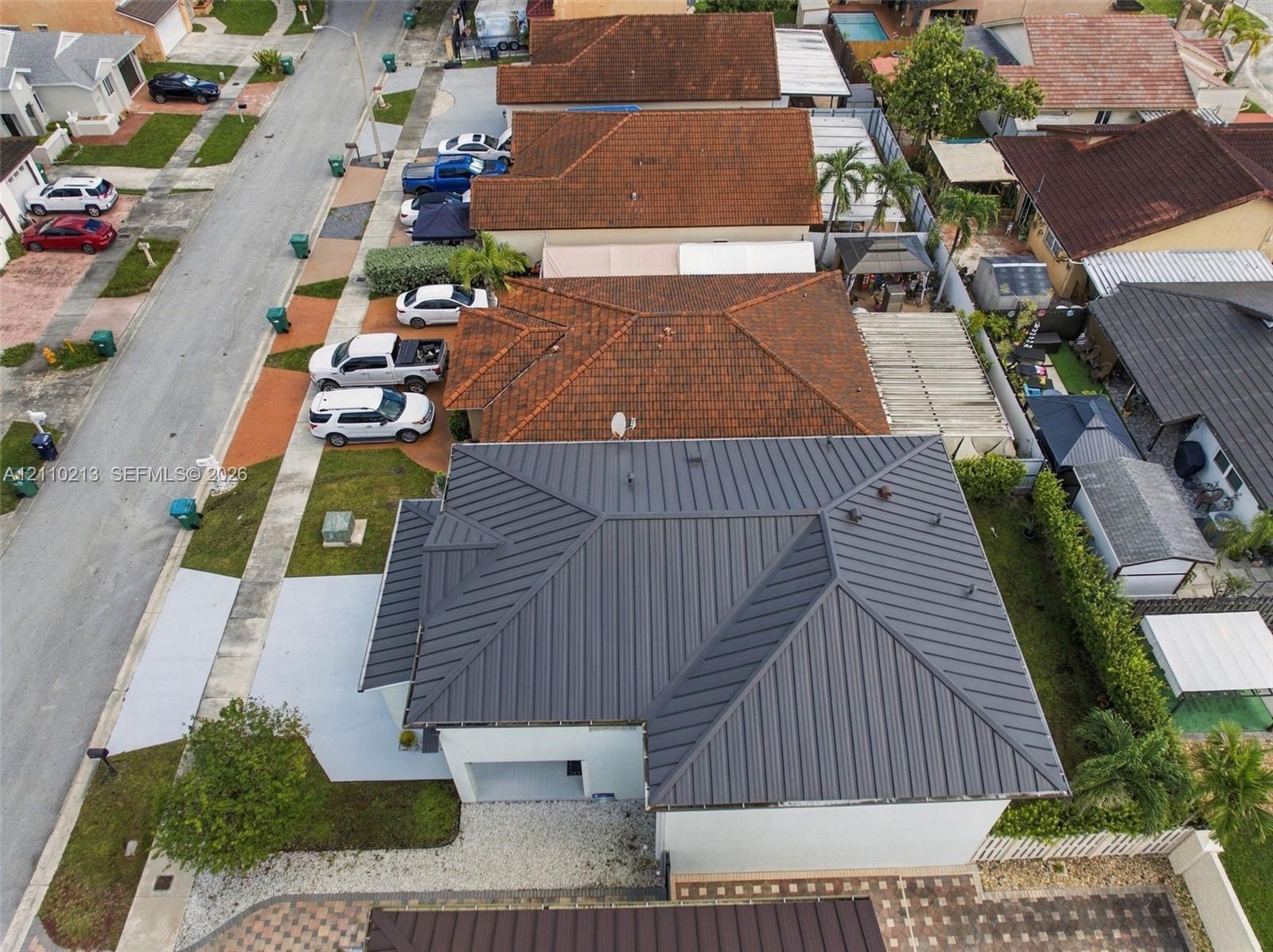 Standing seam metal roof, paved driveway, and side-entry garage