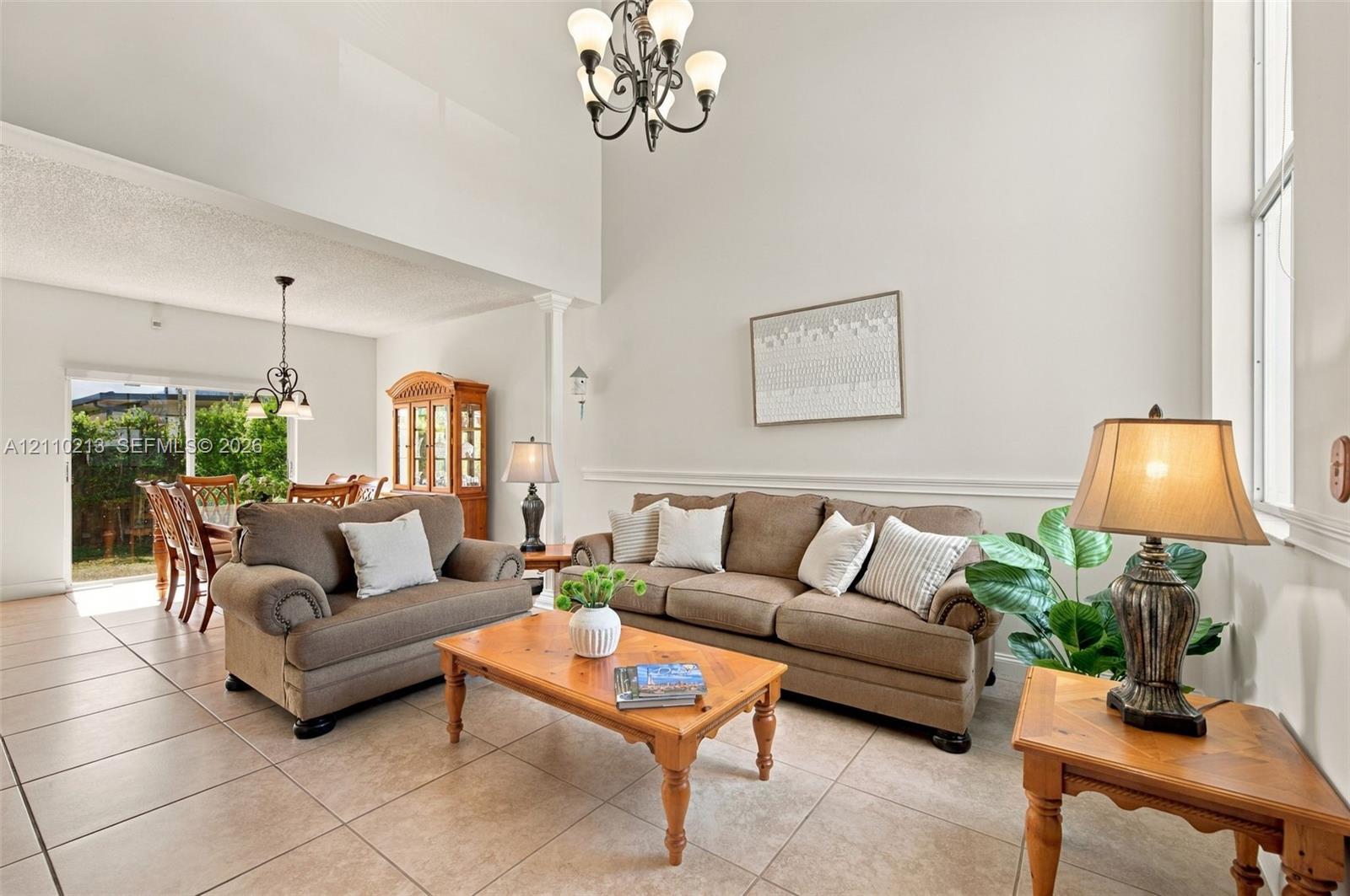 Vaulted ceilings, large-format tile flooring, decorative chair rail molding, and multiple multi-arm chandeliers