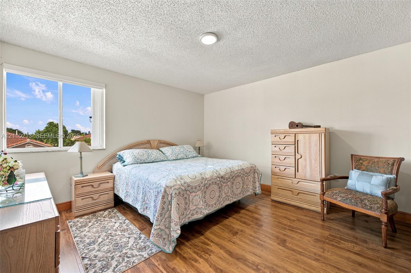Neutral-toned interior walls, wood-finish flooring, and a window with exterior residential scenery