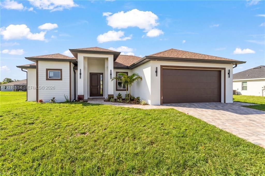 Contemporary stucco exterior featuring a covered entryway, multi-tone shingle roof, two-car garage, and paver driveway