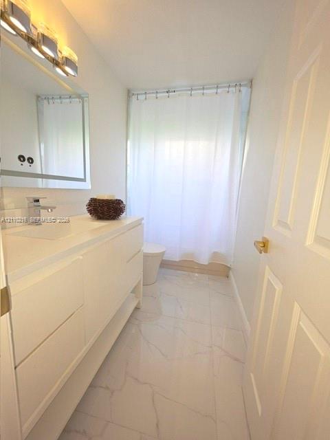 Bathroom featuring a modern white floating vanity with an integrated basin, polished metal faucet, multi-bulb vanity lighting, and light-toned tile flooring