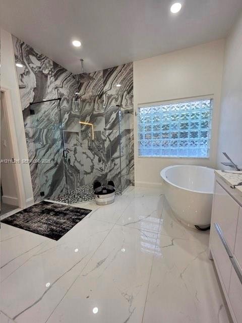 Walk-in shower with floor-to-ceiling patterned stone tile, glass enclosure, and rainfall showerhead, complemented by a freestanding soaking tub, glass block window, and large-format porcelain tile flooring