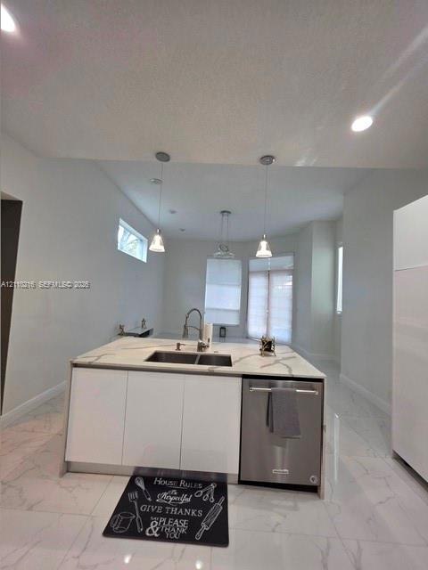 Kitchen island with a light-toned stone-patterned countertop, double-basin undermount sink, integrated stainless steel dishwasher, sleek white cabinetry, and recessed lighting